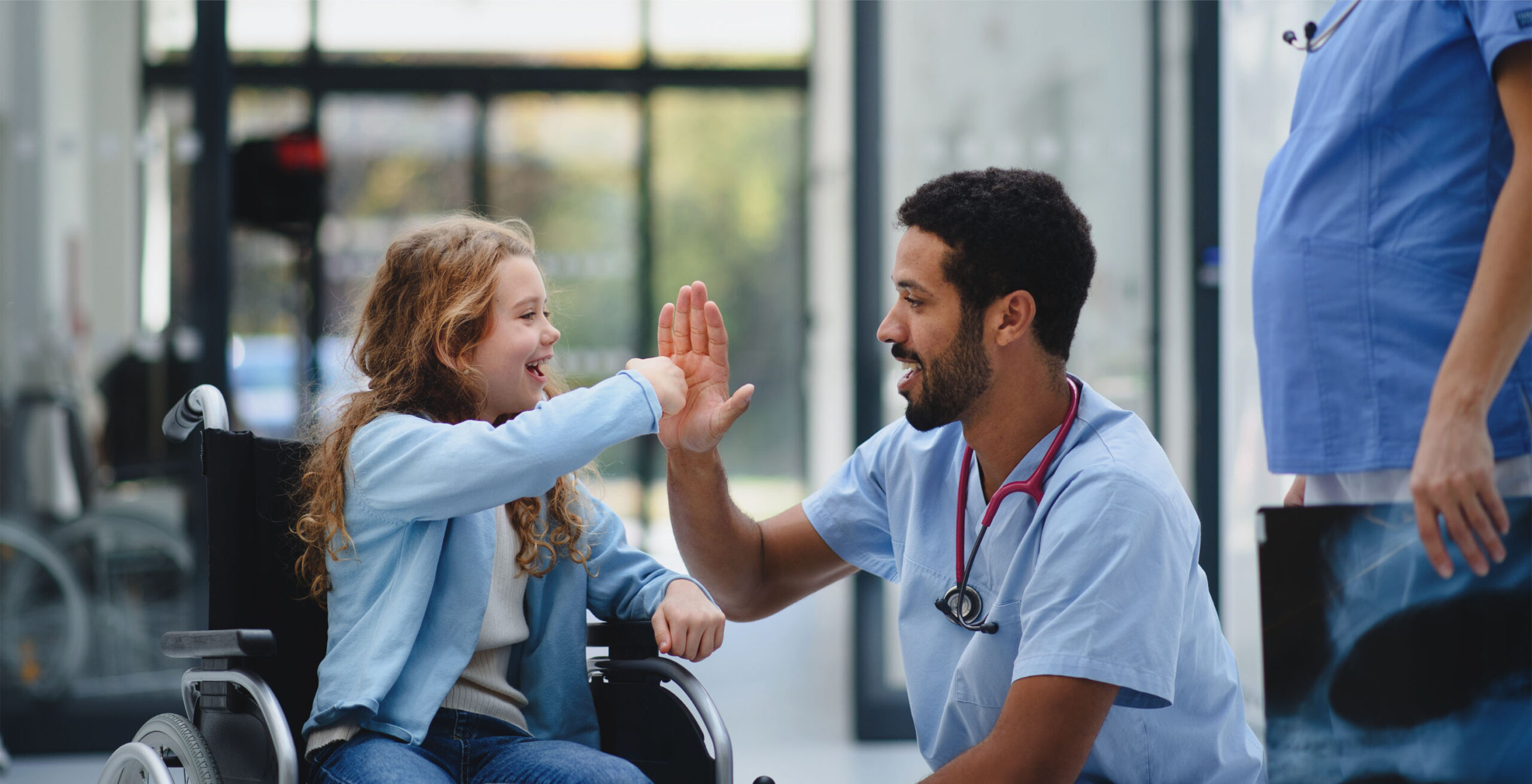 Young white girl in wheelchair high five male nurse.